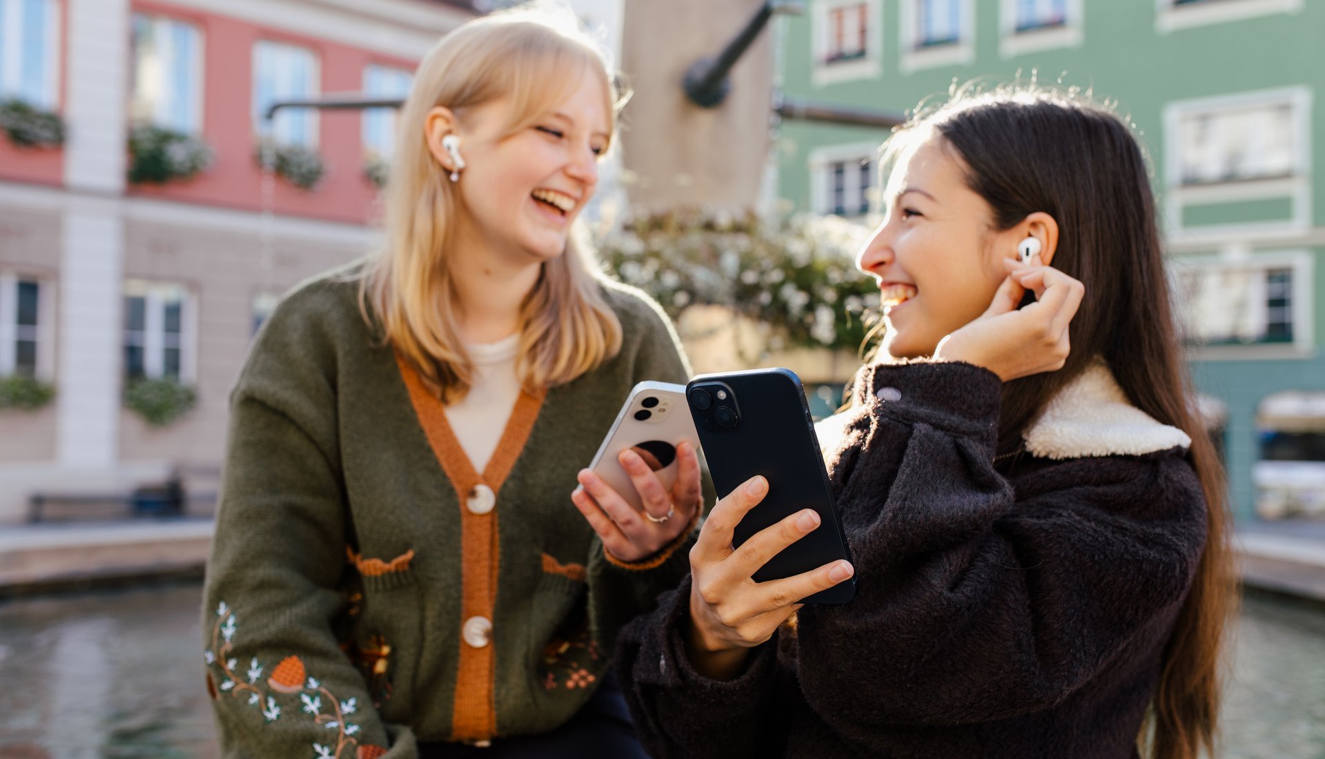 Zwei Freundinnen sitzen am Marktplatz Brunnen und lausche dem Audioguide