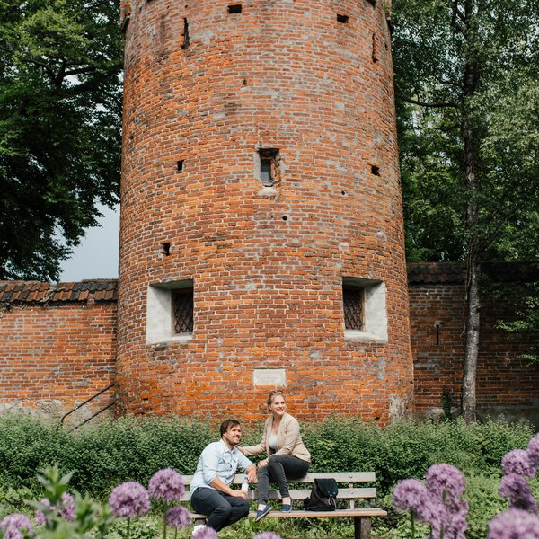 Summer evening at the Swallowtail Tower in Memmingen, where lightness emerges between flowers and historic buildings